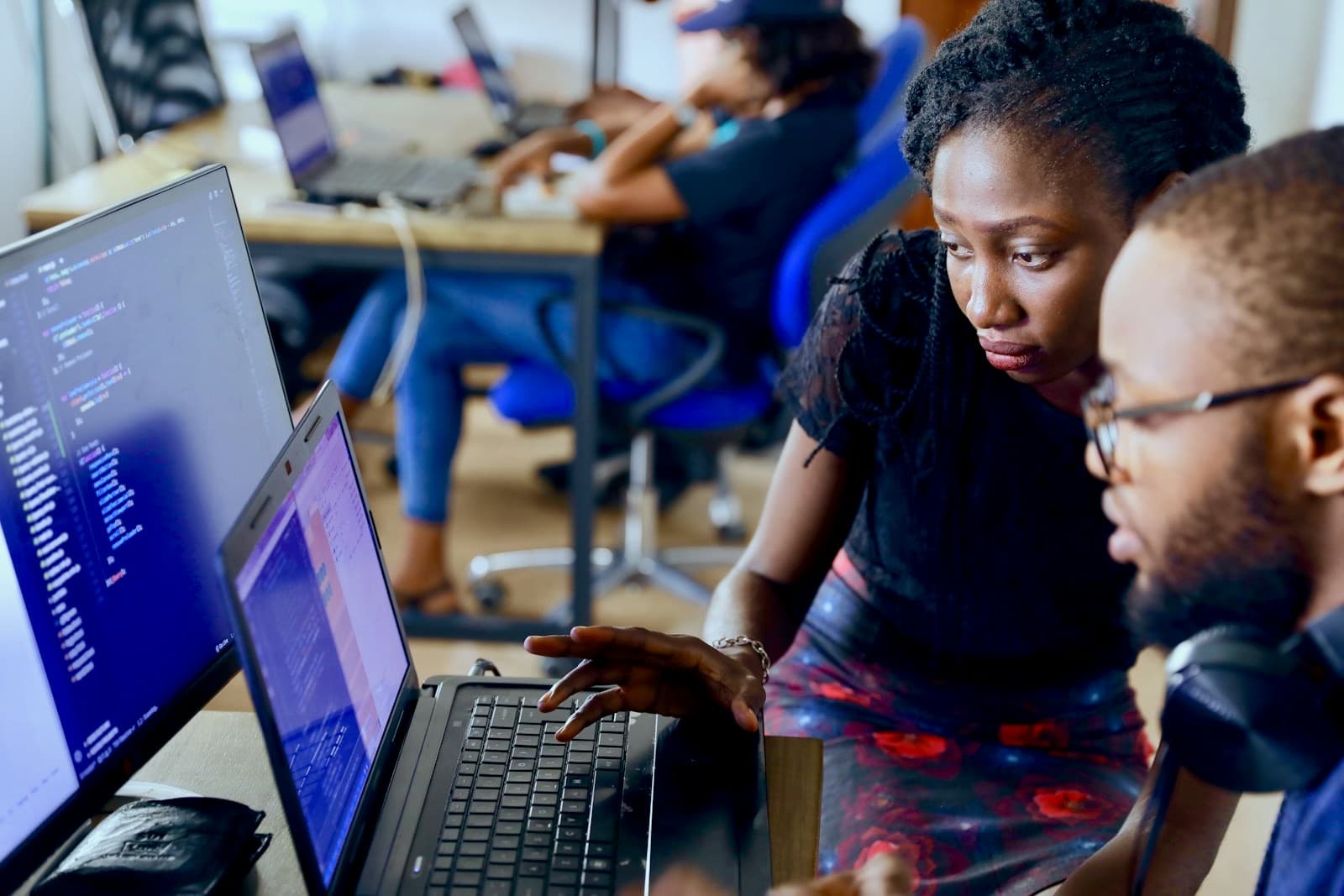 Two developers working on code together in front of a laptop